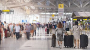 Two women carrying luggage at the airport