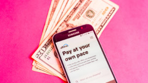 The website for Affirm (AFRM) is shown on a cellphone sitting atop a stack of $20 bills.