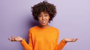 A photograph of a woman shrugging with a confused facial expression.