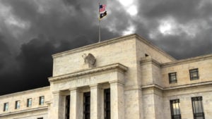 A photo of the entrance of the Federal Reserve Building with dark clouds overhead.
