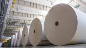 A photo of several large rolls of paper in a warehouse.