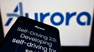 a phone displaying the Aurora website in front of a computer screen displaying the company logo