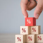 Percentage symbols on wooden cubes stacked in a triangle. The top cube is red. High-Yield stocks to Buy