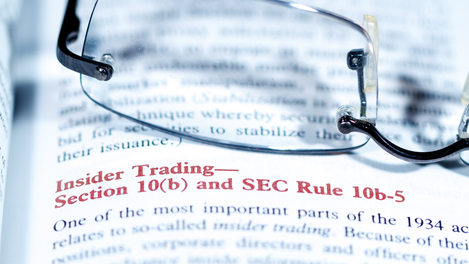 A photograph of a pair of glasses on top of a page with information about SEC insider trading rules.
