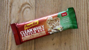 A PowerBar brand protein bar is placed on a wooden surface.