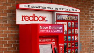 A Redbox (RDBX Stock) kiosk in front of a brick wall.