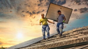 A photo of two men installing a solar panel. Solar stocks