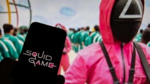 A phone with the "Squid Game" logo displayed on it in front of a TV showing the Netflix show.