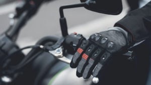 A gloved hand resting on the handles of a motorcycle.