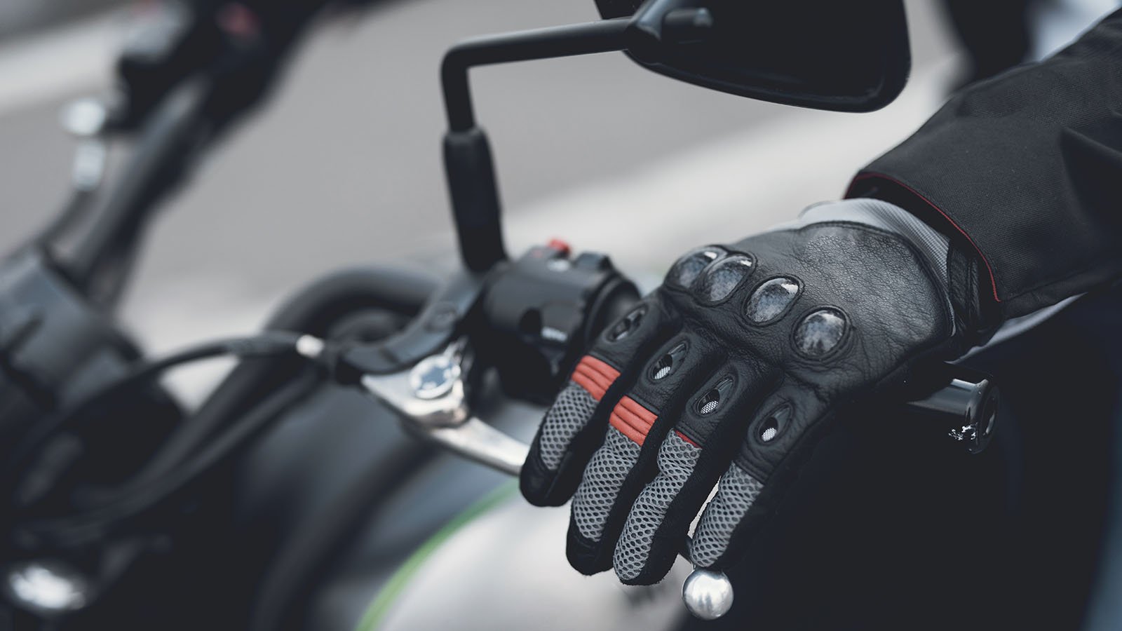 A gloved hand resting on the handles of a motorcycle representing VLCN stock.