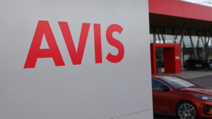 Avis Budget sign in front of a car representing the company's stock.