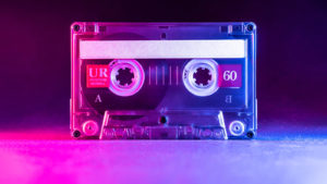A photo of a cassette tape with pink and blue lighting.