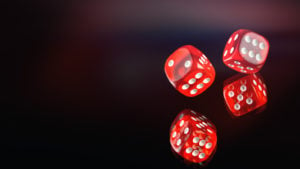 A photo of 2 red dice rolling on a black mirrored background.