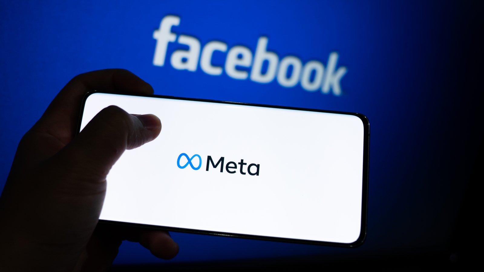 Meta logo is shown on a device screen. Meta is the new corporate name of Facebook.
