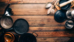 A variety of kitchen supplies are displayed on a wooden surface.