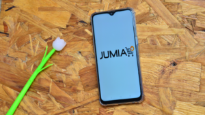 Jumia (JMIA) logo on a cellphone with a flower nearby