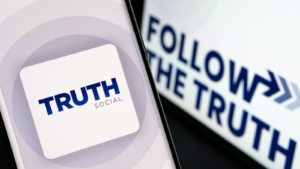 Truth Social app logo seen on the smartphone and the Follow the fruth on blurred screen behind.