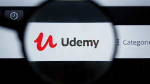 The logo for Udemy (UDMY) is seen through a magnifying glass on the company's website.