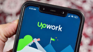 The Upwork (UPWK) logo is displayed on the cellphone.