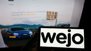 The logo for Wejo in front of the company website.