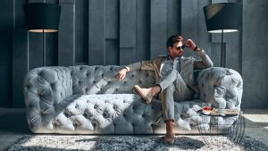 luxury resale stocks Handsome stylish man in beige suit at home sitting on sofa
