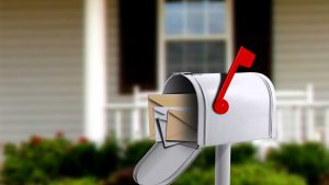 photo of a silver mailbox with red flag up and mail insider, house in background