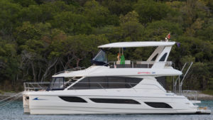Side view of a MarineMax (HZO) boat on the water with trees in background