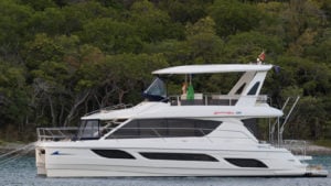 Side view of a MarineMax (HZO) boat on the water with trees in background. dividend stocks to buy