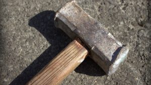 A photo of a sledgehammer on an asphalt surface.