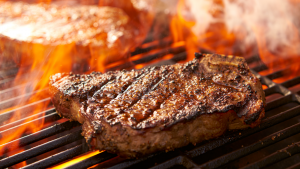 A steak surrounded by flame on a grill representing MITC Stock.