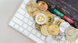 A photo of various crypto coins on a computer keyboard representing TAU Crypto.