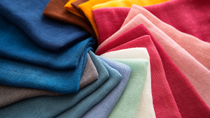 An array of fabric and textiles is arranged on a surface. The fabrics are of all colors; pinks, green, blues, yellows, and browns.