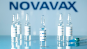 Concept of NVAX stock vaccine against COVID-19. Glass medical vials with liquid. Ampoules with coronavirus vaccine on a medical glass table