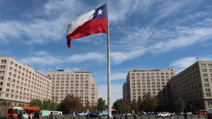 Big waving Chilean national flag symbol on square at La Moneda Palace, urban tourist attraction in business district downtown of capital city Santiago de Chile, Chile