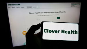 Person holding smartphone with logo of healthcare company Clover Health (CLOV Stock) Investments Corp on screen in front of website