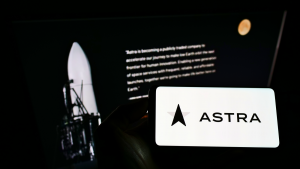 Person holding mobile phone with logo of American aerospace company Astra Space Inc. (ASTR) on screen in front of web page.