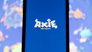 The logo for Axie Infinity (AXS) is displayed on a cellphone screen.