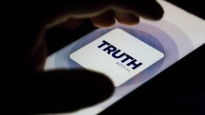 A hand hovers over a phone screen with the Truth Social (DWAC) social media logo