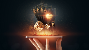 An image of a hand holding a cellphone with dice and playing cards coming from the screen