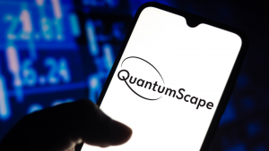 A hand holds a phone and the screen shows the QuantumScape logo. electric vehicle stocks