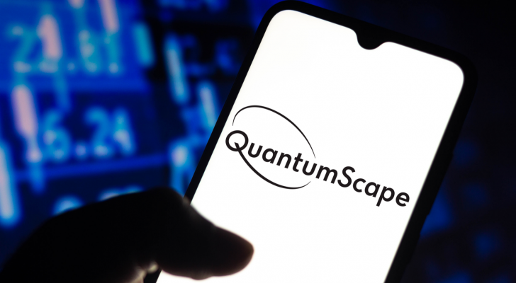 A hand holds a phone and the screen shows the QuantumScape logo