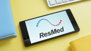 ResMed logo on a tablet on a yellow background. RMD stock.