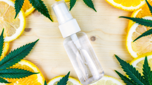 Cannabis Terpene bottle with cannabis leaves and lemon and orange slices on a wooden backdrop
