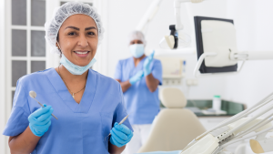 Portrait of smiling hispanic woman dentist preparing tools at modern dental office