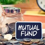 Word Mutual Fund on mini chalkboard and coin in the jar with blurred background of books, green plant and clock