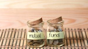 Coins in jar. Writing Mutual Fund on two jar with wooden pallet background.