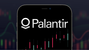 Palantir (PLTR) logo on a smartphone with a set of stock charts in the background.