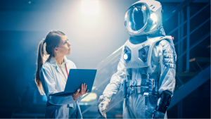 An image of a scientist holding a laptop, looking toward a high-tech spacesuit to the right