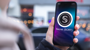 Secret SCRT coin symbol. Trade with cryptocurrency, digital and virtual money, mobile banking. Hand with smartphone, screen with crypto icon close-up