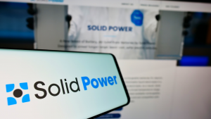 ビジネス Web サイトの前の画面にアメリカの電池会社 Solid Power Inc. のロゴが表示されたスマートフォン。 電話機のディスプレイの中央左に注目します。